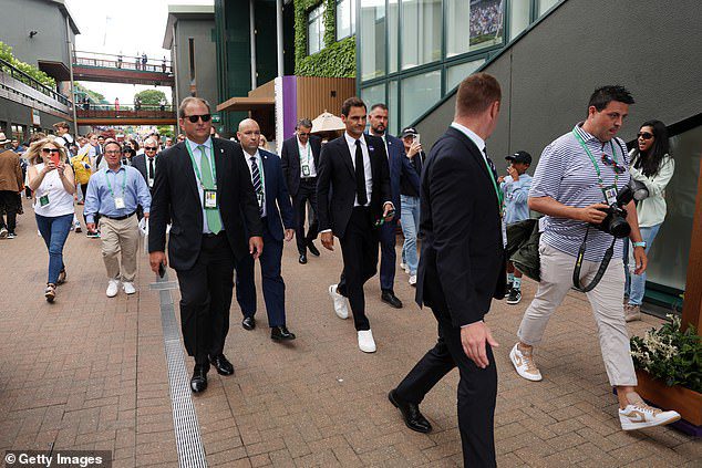 Federer is tracked down by supporters while covering security as he tours SW19