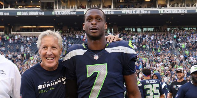 Head coach Pete Carroll of the Seattle Seahawks and No. 7 Geno Smith celebrate their victory over the Arizona Cardinals as they exit Lumen Field on October 16, 2022 in Seattle, Washington. 