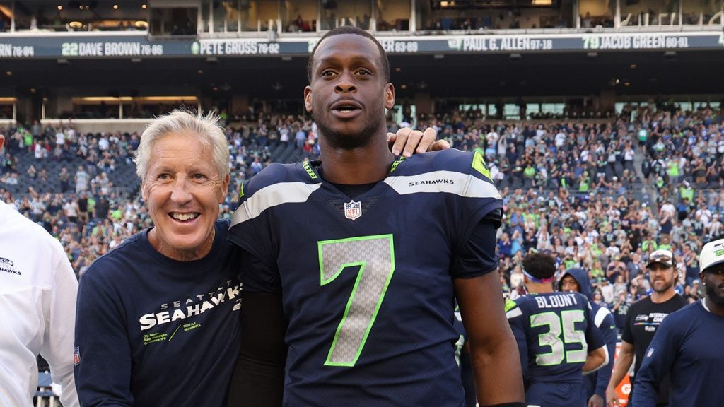 Head coach Pete Carroll of the Seattle Seahawks and Geno Smith #7 celebrate a win against the Arizona Cardinals as they walk off the at  Lumen Field on Oct. 16, 2022 in Seattle, Washington. 